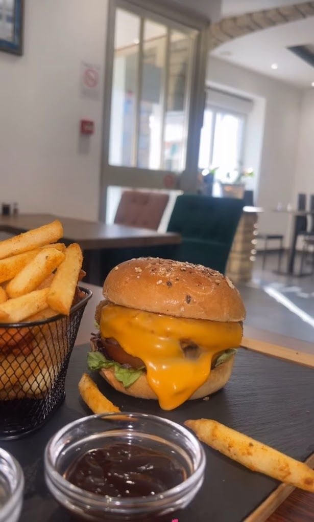 Burger au cheddar fondu et frites épicées servi en salle au Restaurant Élite